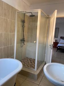a bathroom with a shower and a tub and a sink at Royal Inn Boutique Lodge in Gaborone