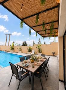a table and chairs on a patio with a pool at Villa Oumnass, Marrakech in Oumnas