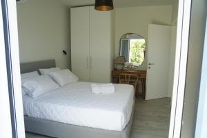 a bedroom with a white bed and a mirror at MENTOROS VILLAS in Karavádhos +76 photos
