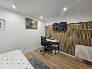 a room with a desk and a tv on a wall at Salons Chènnevières 2 Chambres au Coeur de Conflans in Conflans-Sainte-Honorine