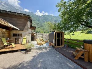 a patio with yellow chairs and a house at Glarner Spa I Private Sauna & Hot Tub & Alps View in Ennenda