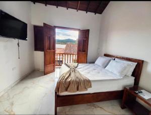 a bedroom with a bed with a tv and a window at Hotel Boutique Porvenir Real in Charalá