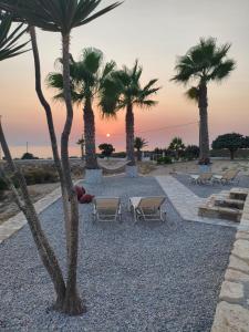 a group of palm trees and chairs on the beach at Aktea Apartments II in Kefalos