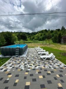 a row of white lounge chairs and a swimming pool at Смерековий двір in Slavske