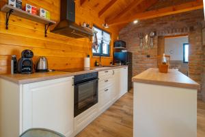 a kitchen with white cabinets and wooden walls at Kuća za odmor Vrata Papuka in Pakrac