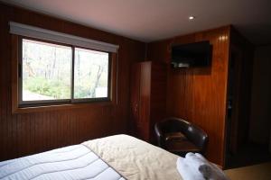 a bedroom with a bed and a window and a chair at Hotel Boutique Anttuy in Las Trancas