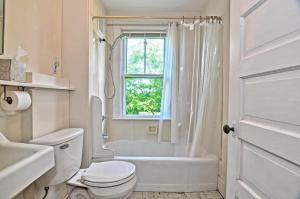 a white bathroom with a toilet and a tub and a window at Westport Point Farmhouse in Westport Point