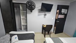a room with two beds and a tv and a chair at aparta hotel continental estadio in Medellín