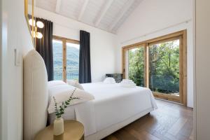 a bedroom with a white bed and a large window at Perla di Mergozzo 2 in Mergozzo