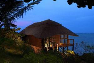 a hut with a large straw umbrella next to the ocean at Melia Zanzibar in Kiwengwa
