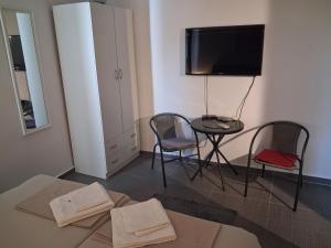 a room with a table and two chairs and a television at Zorin House Rooms in Jezera