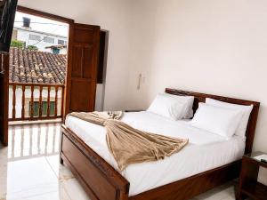 a bedroom with a bed with white sheets and a window at Hotel Boutique Porvenir Real in Charalá