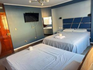 a bedroom with two beds and a tv on the wall at Inti killa in Huánuco +11 photos