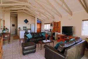 a living room with leather couches and a tv at Baywatch Paternoster - The Penthouse in Paternoster