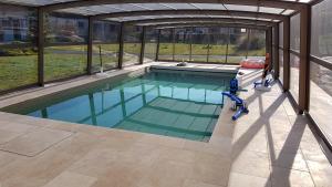 a swimming pool in a house with an open structure at L'Hébergerie in Époye
