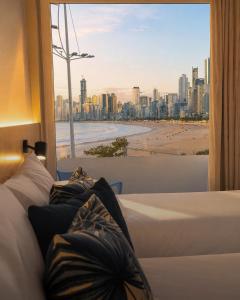 a bedroom with two beds and a view of a beach at Marambaia Hotel e Convenções in Balneário Camboriú