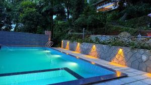 a swimming pool with a stone retaining wall and a stone wall at GAIRAH RESORT in Mundakāyam