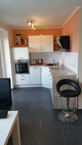 a kitchen with white cabinets and a black stool at Luxusappartement in Meerbusch