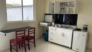 a small kitchen with a counter and two chairs in it at Hostal Villa Franca in Ibarra