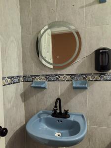 a bathroom sink with a round mirror on the wall at Casa Cariño in San Cristóbal de Las Casas