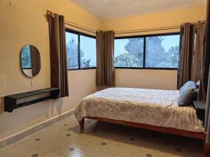 a bedroom with a bed and a mirror and windows at Casa Cariño in San Cristóbal de Las Casas