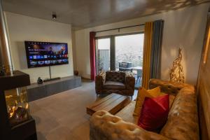 a living room with a couch and a tv at SAUERLAND CHALETS - "Die Chalets Lieblingsplatz" in Winterberg