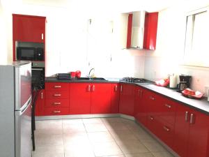 a red kitchen with red cabinets and a refrigerator at Villa Hibiscus in Bouillante +3 photos