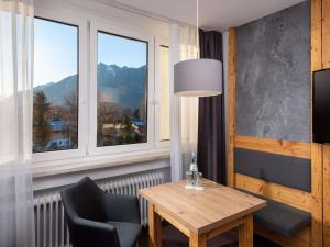 a room with a table and chairs and a window at Sunday Hotel Garmisch Partenkirchen in Garmisch-Partenkirchen