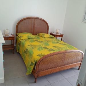 a bed with a yellow comforter and two side tables at Villa Hibiscus in Bouillante
