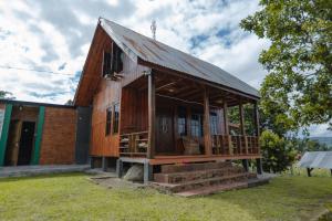 a wooden house with a porch on a grass field at The Wood Cabin in Ambarita +2 photos