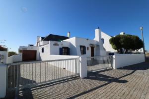 a white house with a gate in front of it at Baywatch Paternoster - The Cottage in Paternoster