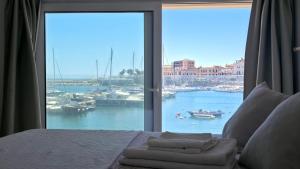 a bedroom with a bed with a view of a harbor at Eos Sea View Apartments in Syracuse