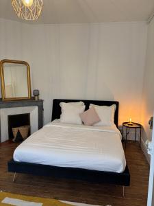 a bedroom with a bed with white sheets and a mirror at Maison Gazel in Castres