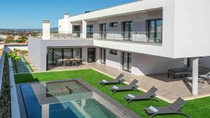 a house with a yard with chairs and a swimming pool at Private Alvor villa with pool and Jacuzzi in Alvor