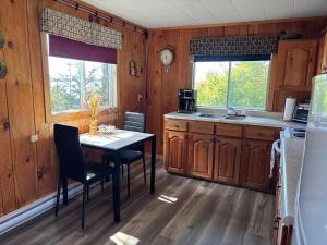 a kitchen with a table and chairs in a room at Bob's Cabin at Wishart's Point Lodge in Neguac