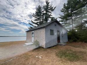 a small white building sitting next to a body of water at Bob's Cabin at Wishart's Point Lodge in Neguac