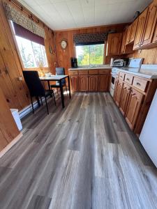 a kitchen with wooden flooring and a table in a room at Bob's Cabin at Wishart's Point Lodge in Neguac