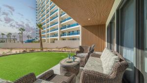 a patio with wicker chairs and a table and a lawn at Encantame Soleil Ground Floor Getaway in Playa Encanto
