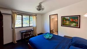a bedroom with a blue bed and a window at El Clan Hostel in Puerto Viejo +39 photos