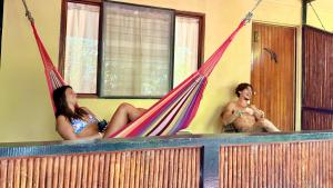 two women and a man sitting in hammocks in a room at El Clan Hostel in Puerto Viejo