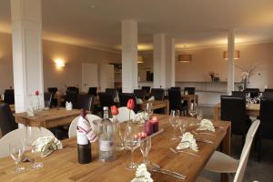 a dining room with wooden tables with wine glasses at Reetdachhotel - Residenz am Ostufer in Boek +59 photos