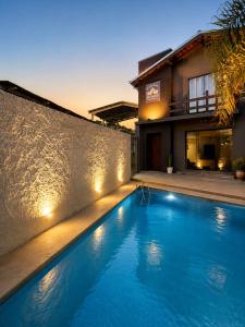 a swimming pool with lights in front of a house at Pousada Estação Rio Branco in Votuverava