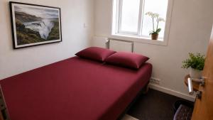 a red bed in a room with a window at 105 Guesthouse Hotel in Reykjavík