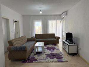 a living room with two couches and a tv at Unik Apartment in Kosovo Polje