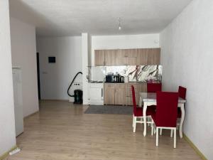 a kitchen with a table and red chairs in a room at Unik Apartment in Kosovo Polje
