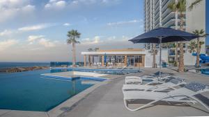 a hotel swimming pool with chairs and an umbrella at Encantame Velero Ground Floor, BeachFront in Playa Encanto