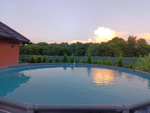 a large swimming pool with a sunset in the background at Apartman A&E in Živinice