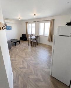 a living room with a table and a refrigerator at Cosy appartement in Miniac-Morvan