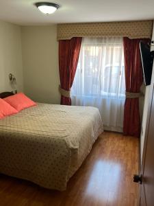 a bedroom with a bed and a window with red curtains at DUNA Apart Hotel in Copiapó +13 photos