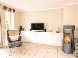 a living room with a fireplace and a tv and a chair at Haus "Carla Marie" in Hedehusum +35 photos